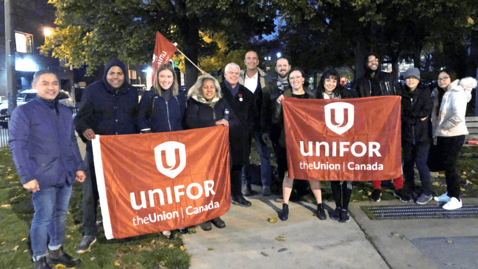 A group of Unifor members hold Unifor flags.